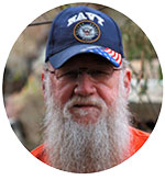 Jess, a veteran and migraine patient, smiling while wearing a Navy hat.